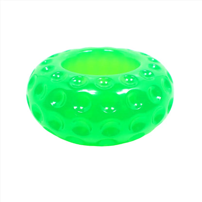 Side view of the small handmade resin succulent pot. It is short round saucer shaped with indented round dots all the way around it. There is an opening at the top for putting a succulent or tiny items. It is bright neon green in color.