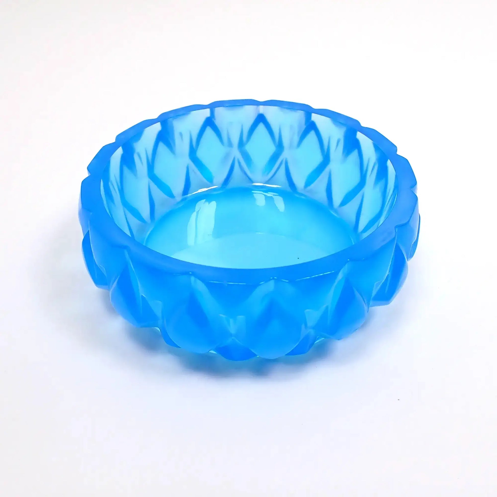 Side view of the small handmade short round succulent pot. It has a short round shape with bright neon blue resin. There is a diamond shaped pattern going all the way around. The large opening on top is wide for putting small plants or using as a trinket dish.
