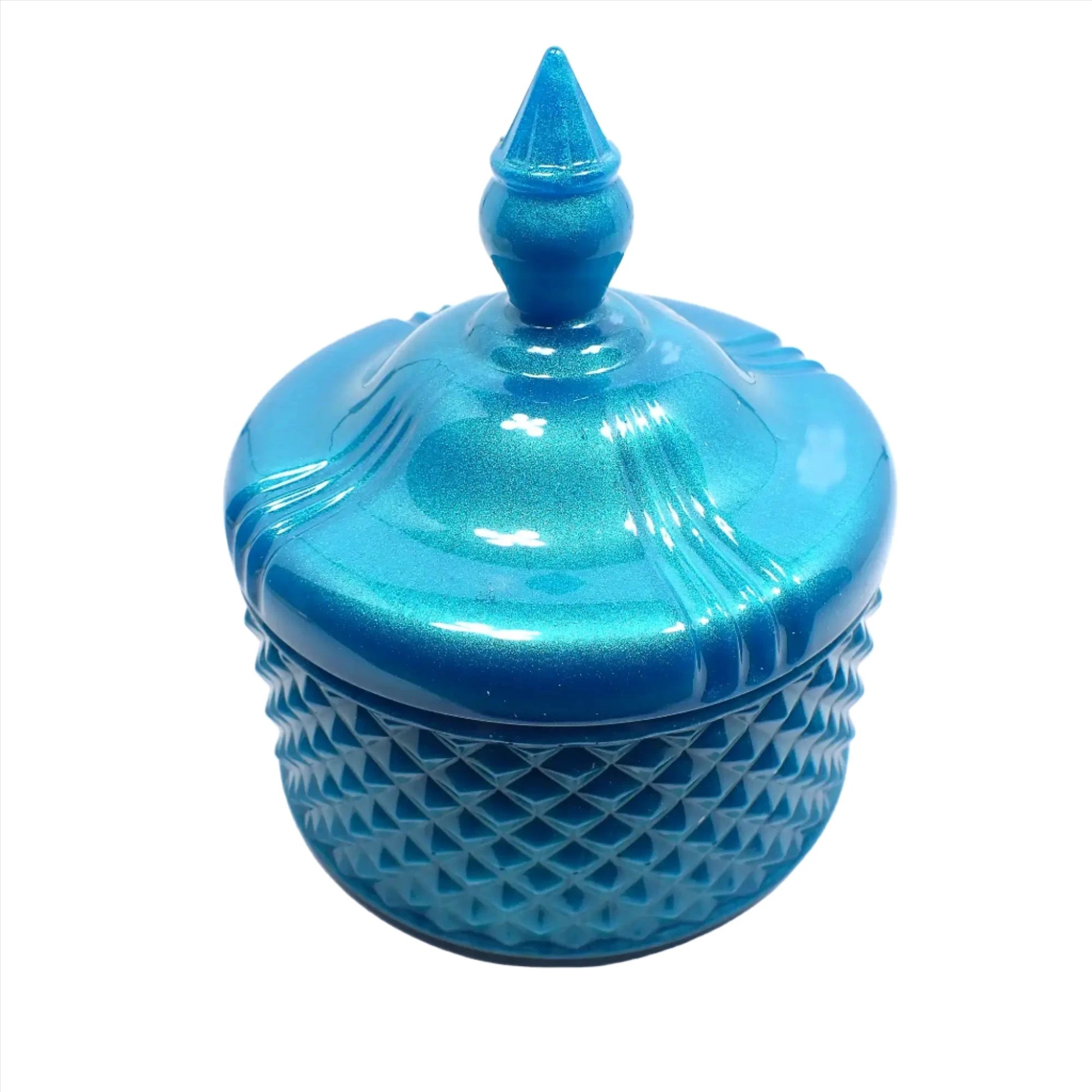 Side view of the pearly aqua blue trinket candy dish. The bottom part has a textured bumpy diamond shaped design all the way around it. The piece itself has a rounded shape. The lid is smooth with some indented lines going down the curves as it tapers at the top. The very top of the lid has a tapered cone shape to grab onto so you can lift the lid off the trinket box.