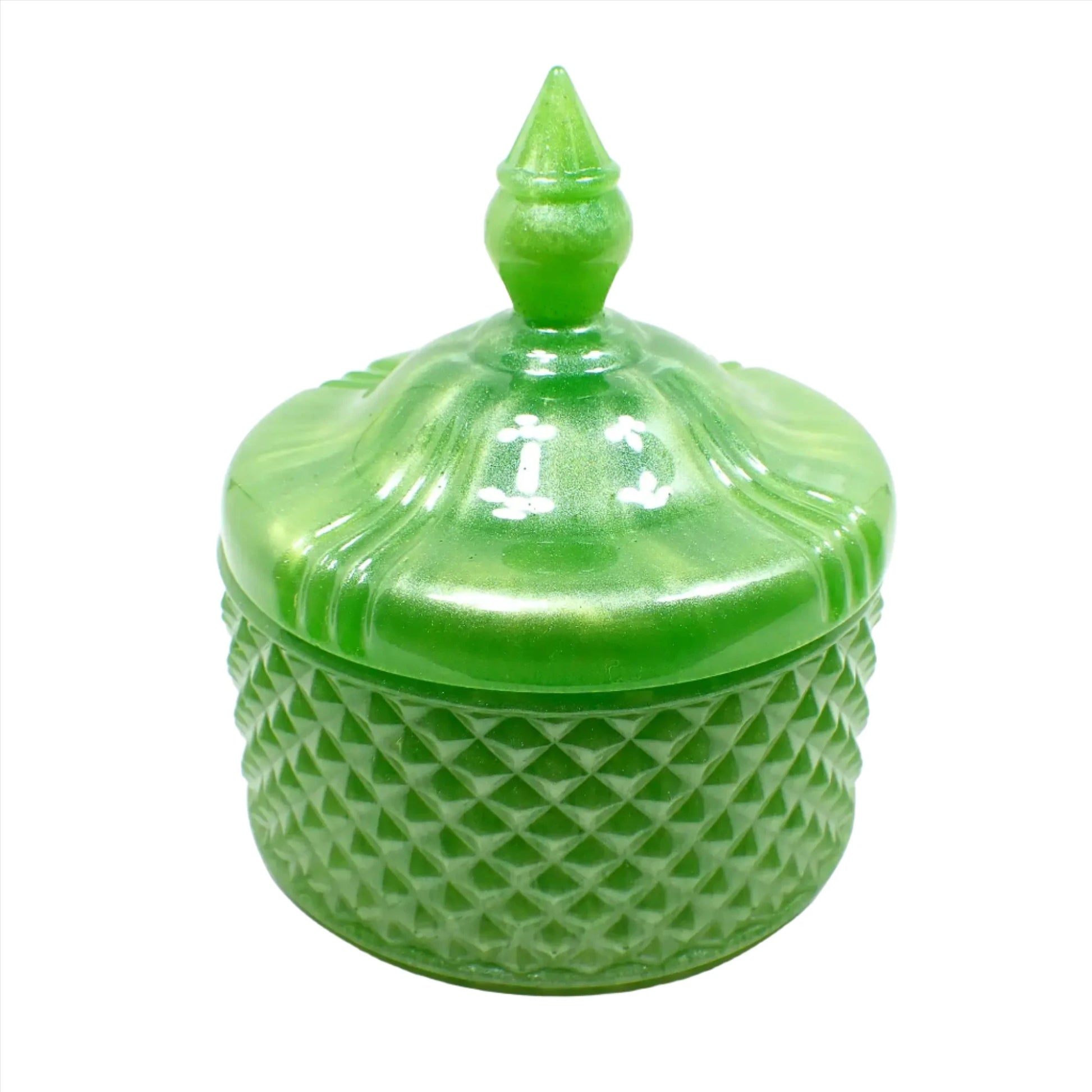 Side view of the pearly lime green trinket candy dish. The bottom part has a textured bumpy diamond shaped design all the way around it. The piece itself has a rounded shape. The lid is smooth with some indented lines going down the curves as it tapers at the top. The very top of the lid has a tapered cone shape to grab onto so you can lift the lid off the trinket box.