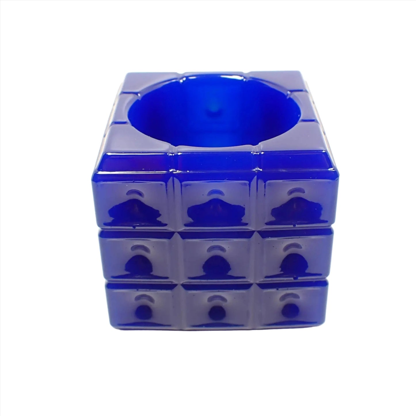 Angled photo of the handmade resin trinket dish. The resin is opaque royal blue in color. The dish is cube shaped with a square pattern all the way around the edge. The top has a round open area to put small things.