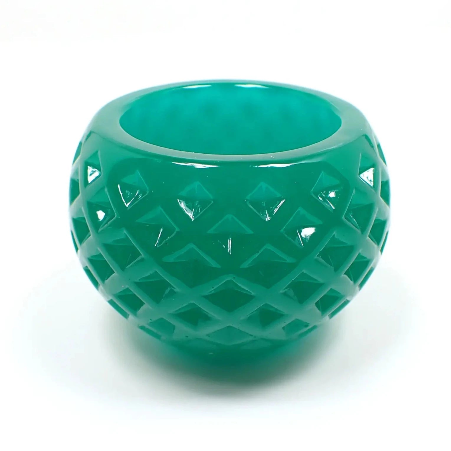 Side view of the small handmade resin succulent pot. In this lighting it's showing as teal green. It is round shaped the an indented diamond shape pattern design all the way around it.