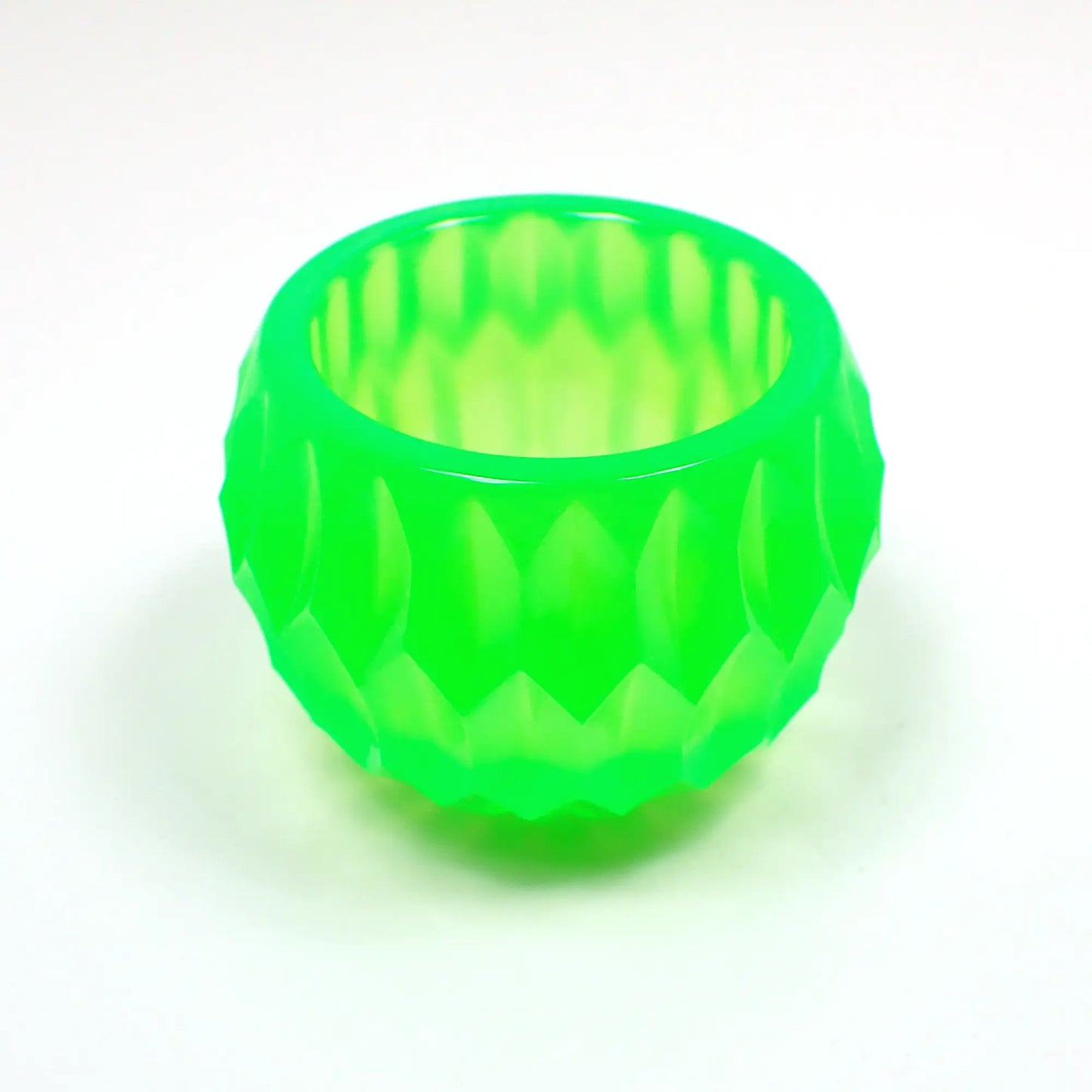 Angled view of the handmade resin small succulent pot decorative bowl. It is bright neon green in color and has a rounded shape with an indented hexagon pattern.