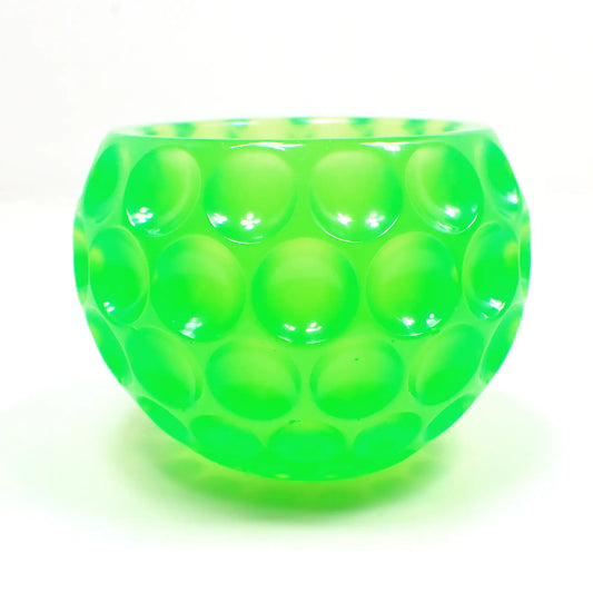 Side view of the handmade resin decorative bowl. The resin is bright neon green in color. The bowl is rounded and has an indented dot design all the way around it.