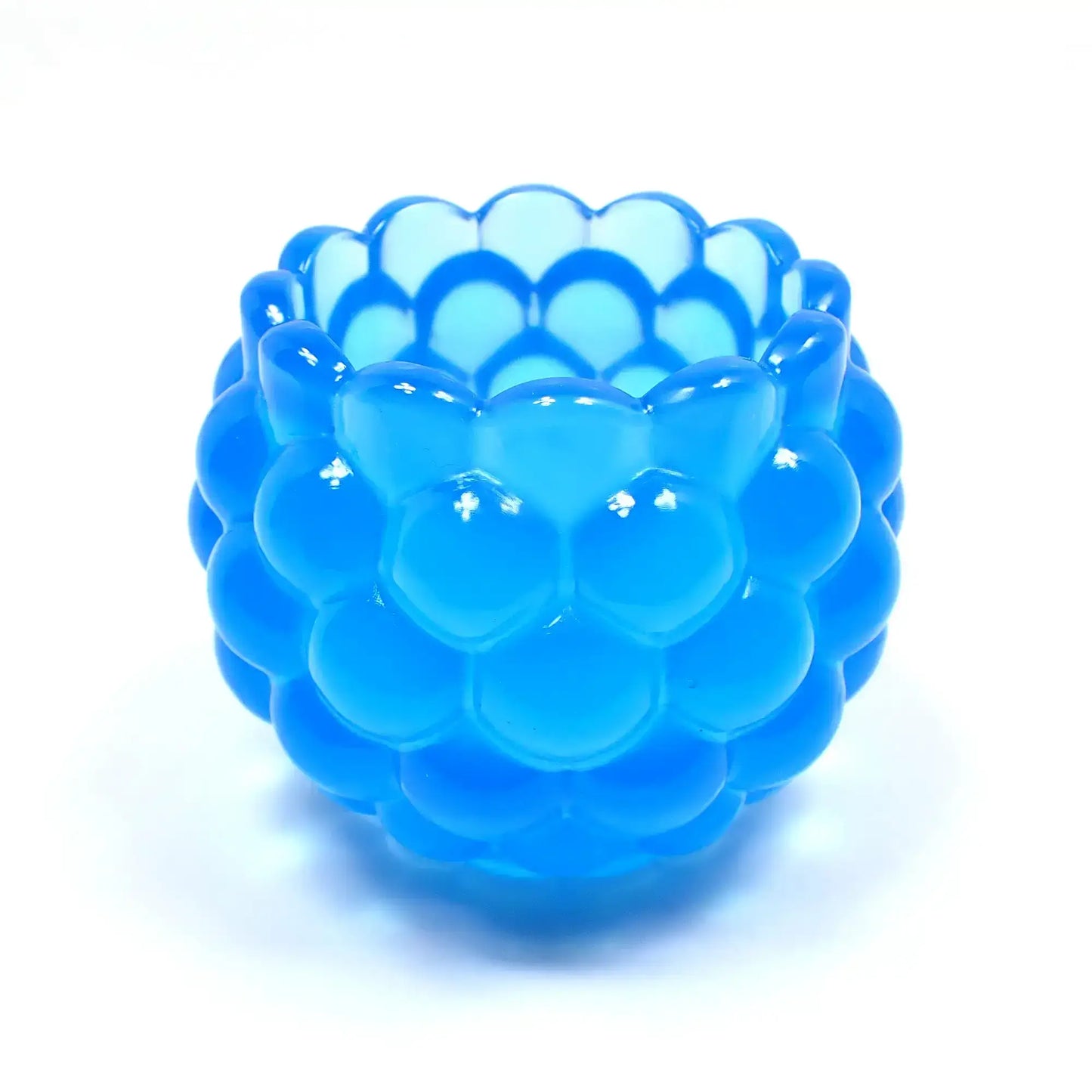 Side view of the handmade resin decorative bowl. The resin is neon blue in color. It has a rounded shape with a bumpy round ball textured on the outside. The top tapers slightly and has a scalloped edge.