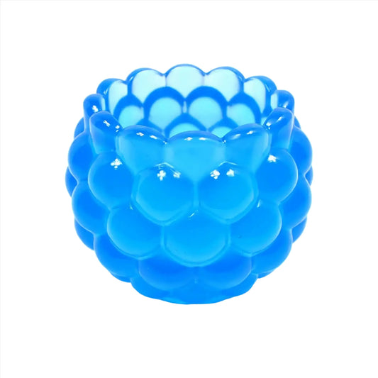Side view of the handmade resin decorative bowl. The resin is neon blue in color. It has a rounded shape with a bumpy round ball textured on the outside. The top tapers slightly and has a scalloped edge.