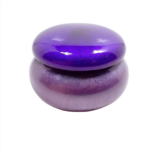Side view of the small handmade round trinket box jar with lid. It is short round in shape with a pearly bright purple lid and a pearly light purple bottom.