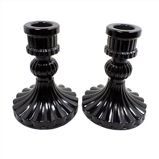 Side view of the handmade vintage style Goth candlestick holders. They have shiny black resin and a ripple style corrugated design with a flared out round bottom.