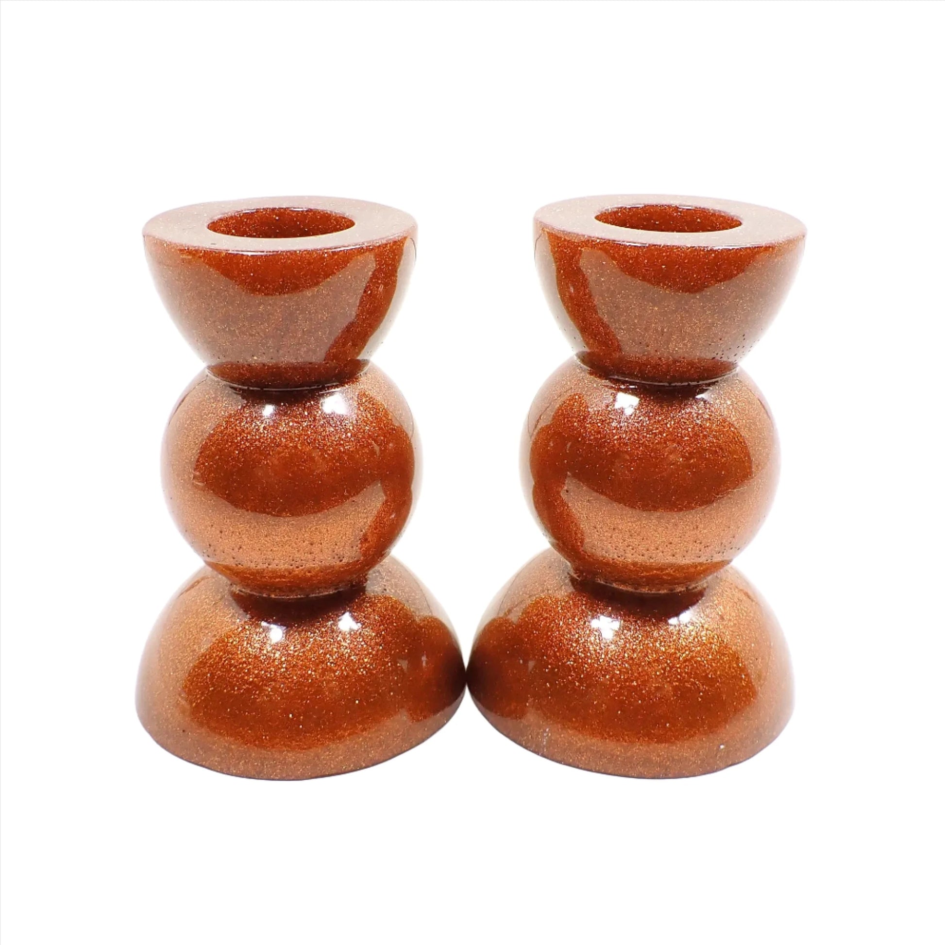 Side view of the handmade geometric candlestick holders. They have three rounded areas with a flared out top and bottom. The resin is sparkly copper in color.