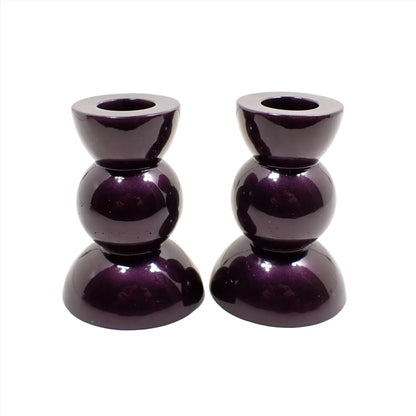 Side view of the handmade geometric candlestick holders. They have a round ball area in the middle and a semi sphere shape on the top and bottom. The resin is a dark shade of deep purple. 