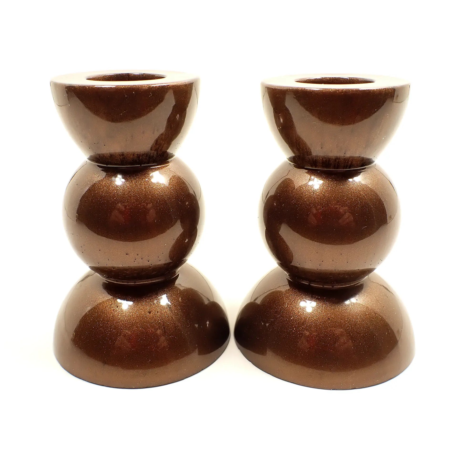 Side view of the handmade geometric candlestick holders. They have a round ball area in the middle and a semi sphere shape on the top and bottom. The resin is a pearly chocolate brown color.