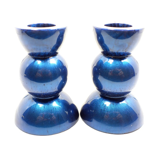 Side view of the handmade geometric candlestick holders. They have a round ball area in the middle and a semi sphere shape on the top and bottom. The resin is a pearly bright denim blue color.