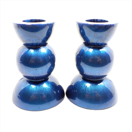 Side view of the handmade geometric candlestick holders. They have a round ball area in the middle and a semi sphere shape on the top and bottom. The resin is a pearly bright denim blue color.
