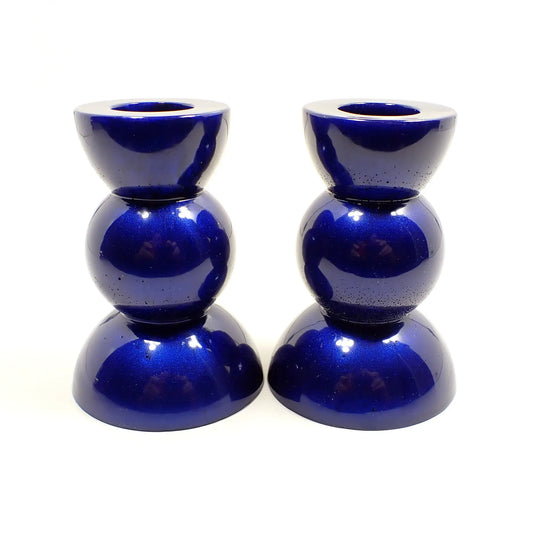 Side view of the handmade geometric candlestick holders. They have a round ball area in the middle and a semi sphere shape on the top and bottom. The resin is a pearly cobalt blue color.