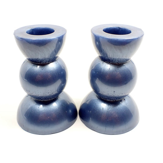 Side view of the handmade geometric candlestick holders. They have a round ball area in the middle and a semi sphere shape on the top and bottom. The resin is a pearly light blue color.