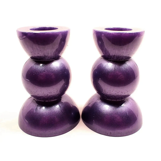 Side view of the handmade geometric candlestick holders. They have a round ball area in the middle and a semi sphere shape on the top and bottom. The resin is a pearly lilac purple color.