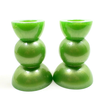 Side view of the handmade geometric candlestick holders. They have a round ball area in the middle and a semi sphere shape on the top and bottom. The resin is a pearly lime green color.
