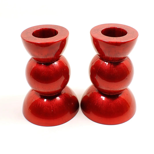 Side view of the handmade geometric candlestick holders. They have a round ball area in the middle and a semi sphere shape on the top and bottom. The resin is a rich pearly red color.