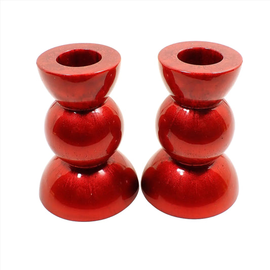 Side view of the handmade geometric candlestick holders. They have a round ball area in the middle and a semi sphere shape on the top and bottom. The resin is a rich pearly red color.