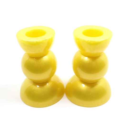 Side view of the handmade geometric candlestick holders. They have a round ball area in the middle and a semi sphere shape on the top and bottom. The resin is a bright pearly yellow color.