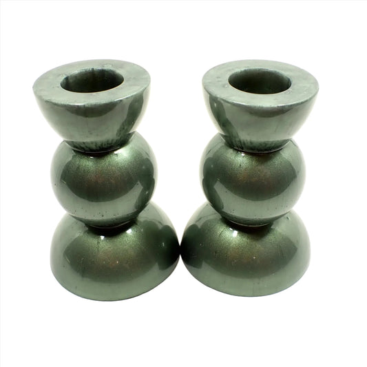 Side view of the handmade geometric candlestick holders. They have a round ball area in the middle and a semi sphere shape on the top and bottom. The resin is a pearly light olive green color.