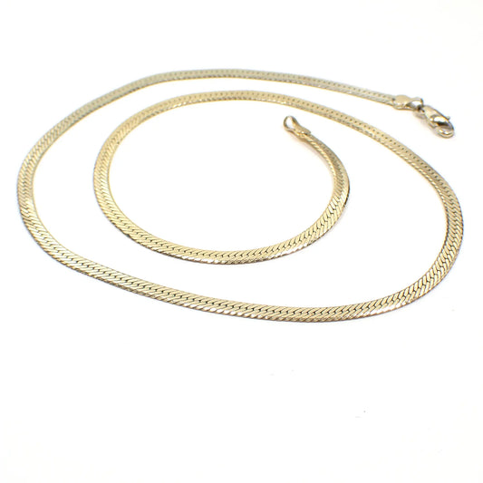 The 1990's vintage herringbone link necklace. It is a lighter color gold tone with lobster claw clasp at the end.