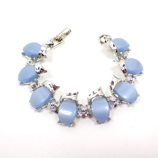 Top view of the 1950's Mid Century vintage thermoset bracelet. The metal is silver tone in color. The links have light blue curved thermoset plastic cabs with a small flower shape in between each link. The snap lock clasp at the end is showing some plating damage from age.