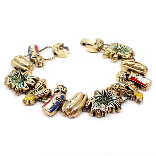 Top view of the retro vintage 4th of July slide charm bracelet. There are firecracker, rocket, firework burst, and hot dog charms. Most of the charms have some colored enamel on them. There is a slide lock clasp at the end.