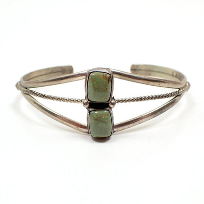 Front view of the retro vintage Wayne Estitty Navajo sterling silver and green turquoise cuff bracelet. it has an open curved design with a twisted curved wire in the middle. There are two puffy rectangle green turquoise cabs on the front. 