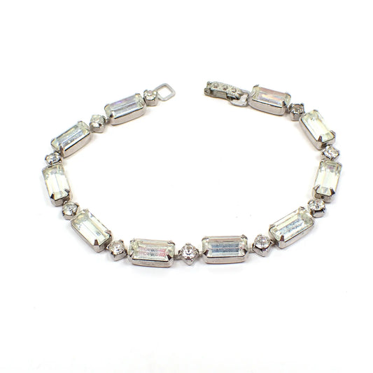Top view of the 1950's Mid Century vintage rhinestone bracelet. The metal is silver tone in color. There are small round rhinestones in between larger baguette shaped rhinestone links. There is a snap lock clasp at the end.