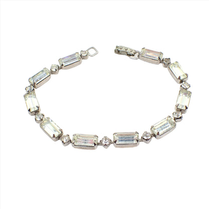 Top view of the 1950's Mid Century vintage rhinestone bracelet. The metal is silver tone in color. There are small round rhinestones in between larger baguette shaped rhinestone links. There is a snap lock clasp at the end.