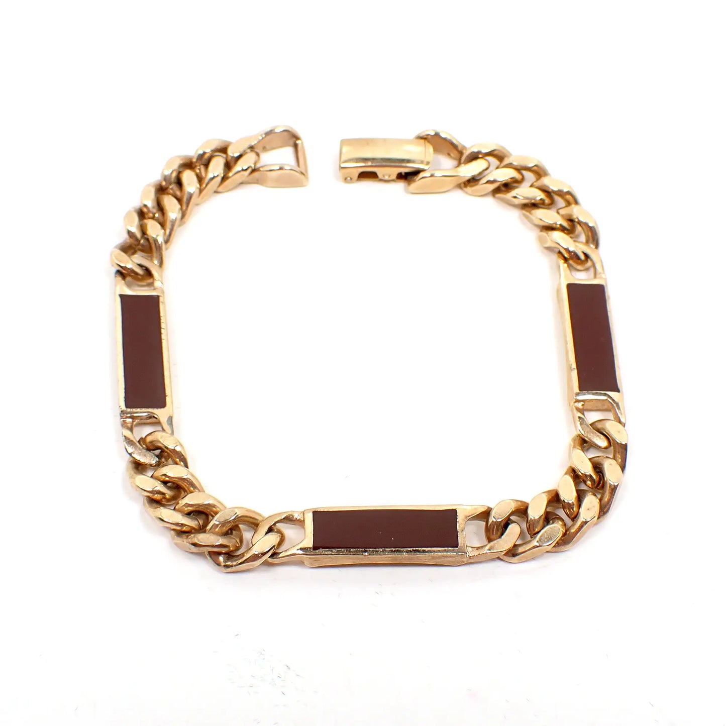 Top view of the retro vintage Avon enameled link chain bracelet. The metal is gold tone in color. There are three rectangle bar links that are burgundy colored enameled in between wider curb chain. There is a snap lock clasp at the end.