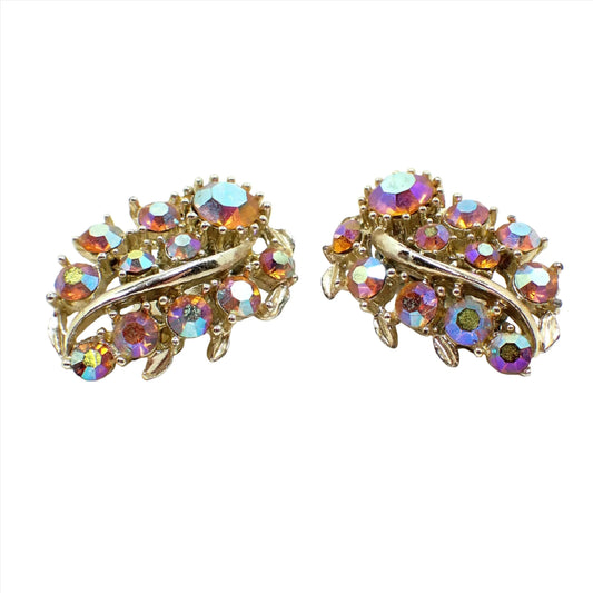 Front view of the Mid Century vintage rhinestone earrings. The earrings are shaped like leaves with gold tone color metal. There are round AB orange rhinestones dispersed throughout the fronts of the earrings.