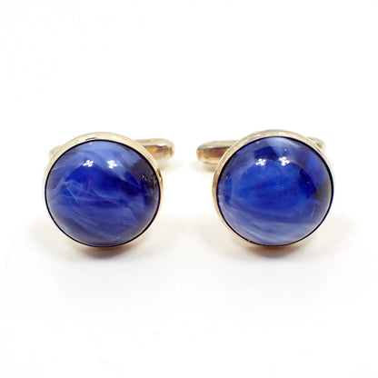 Front view of the Hickok Mid Century vintage lucite cufflinks. They are round in shape and have a gold tone color metal setting. The domed lucite cabs are mostly blue with areas of white marbled in. 