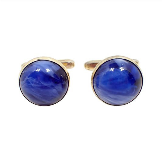 Front view of the Hickok Mid Century vintage lucite cufflinks. They are round in shape and have a gold tone color metal setting. The domed lucite cabs are mostly blue with areas of white marbled in. 