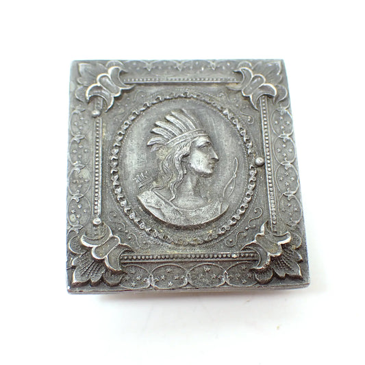 Front view of the retro vintage Bergamot Brass works vintage belt buckle. It is rectangle in shape and dark pewter gray in color. There is an oval in the middle with a cameo portrait depiction of a Native American. The rest of the buckle has a detailed Art Nouveau like design.