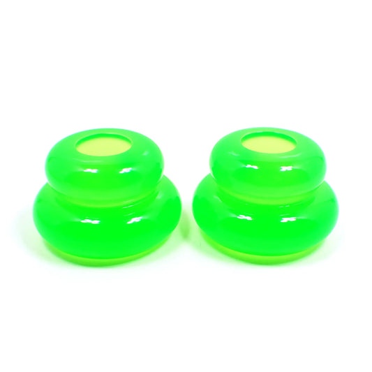 Side view of the pair of handmade double ring candlestick holders. They are shaped like puffy donut rings with a larger one on bottom and a smaller one on top. The resin is bright neon green in color. There is a round hole at the top for the candlesticks to go in.