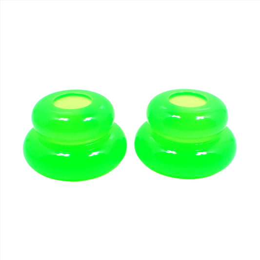 Side view of the pair of handmade double ring candlestick holders. They are shaped like puffy donut rings with a larger one on bottom and a smaller one on top. The resin is bright neon green in color. There is a round hole at the top for the candlesticks to go in.