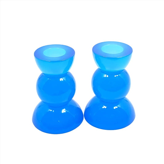 Side view of the handmade neon resin rounded geometric candlestick holders. They are neon blue in color. They are shaped with a semi circle at the top and bottom with a sphere shape in between.
