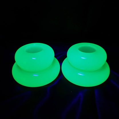 Photo showing the handmade neon green resin candlestick holders fluorescing under a UV light in a bright green color.