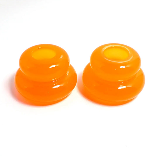 Side view of the pair of handmade double ring candlestick holders. They are shaped like puffy donut rings with a larger one on bottom and a smaller one on top. The resin is neon orange in color. There is a round hole at the top for the candlesticks to go in.