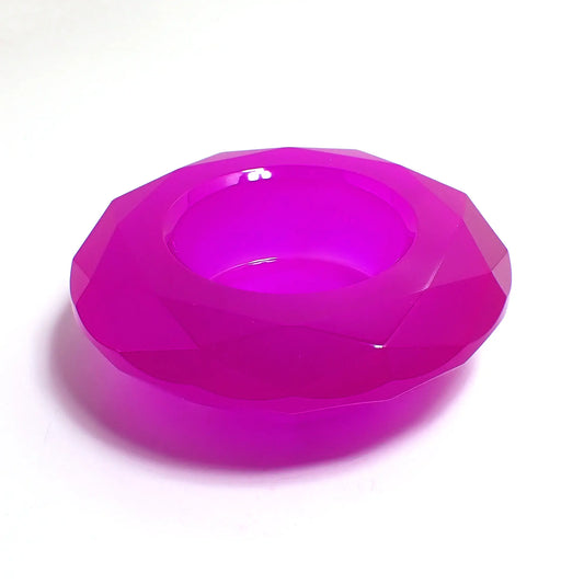Photo of the handmade resin decorative pot. The resin is neon purple in color. It has a faceted round shape that tapers down on the bottom. There is a circular opening in the middle to put things. 