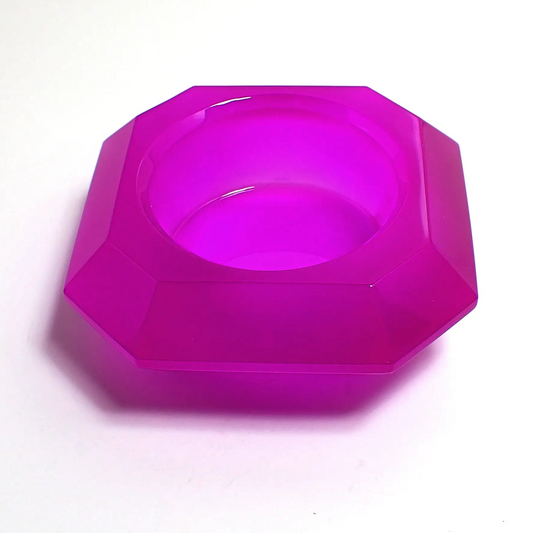 Photo of the handmade resin geometric decorative pot. The resin is neon purple in color. It has a faceted octagon shape that tapers down to the bottom. There is a circular opening in the middle to put things.