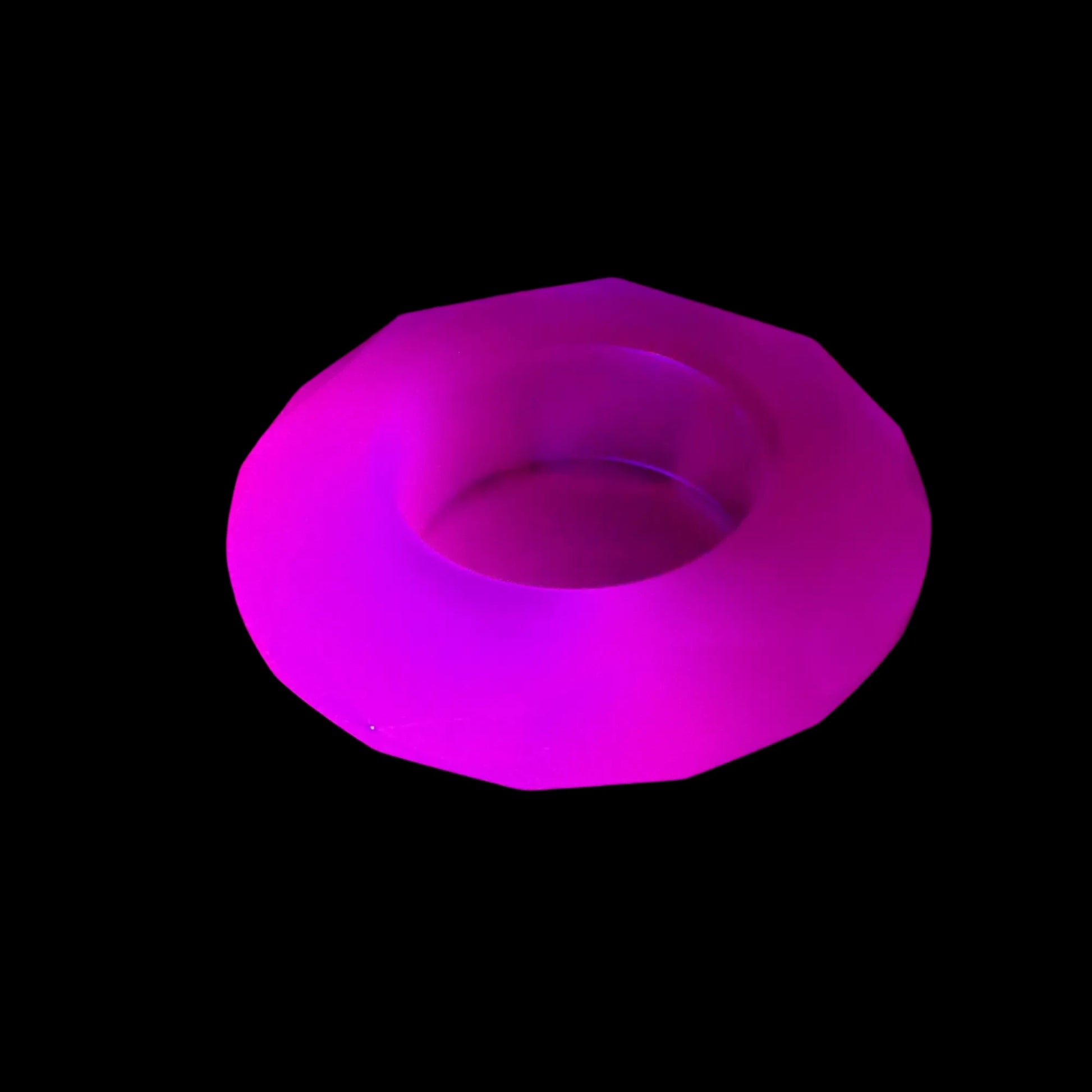 Photo of the handmade neon purple resin faceted round decorative pot fluorescing pink under a UV light.