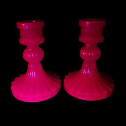 Photo of the vintage style handmade neon purple resin candlestick holders fluorescing pink under a UV light.