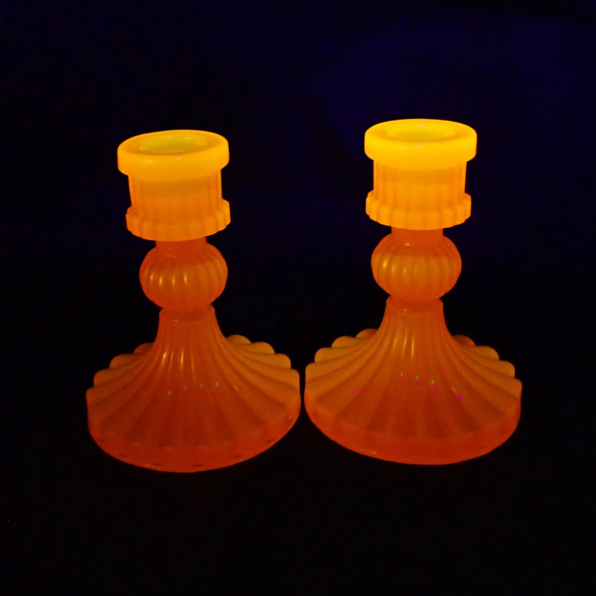 Photo showing how the vintage style handmade resin neon orange candlestick holders fluoresce under a UV light.