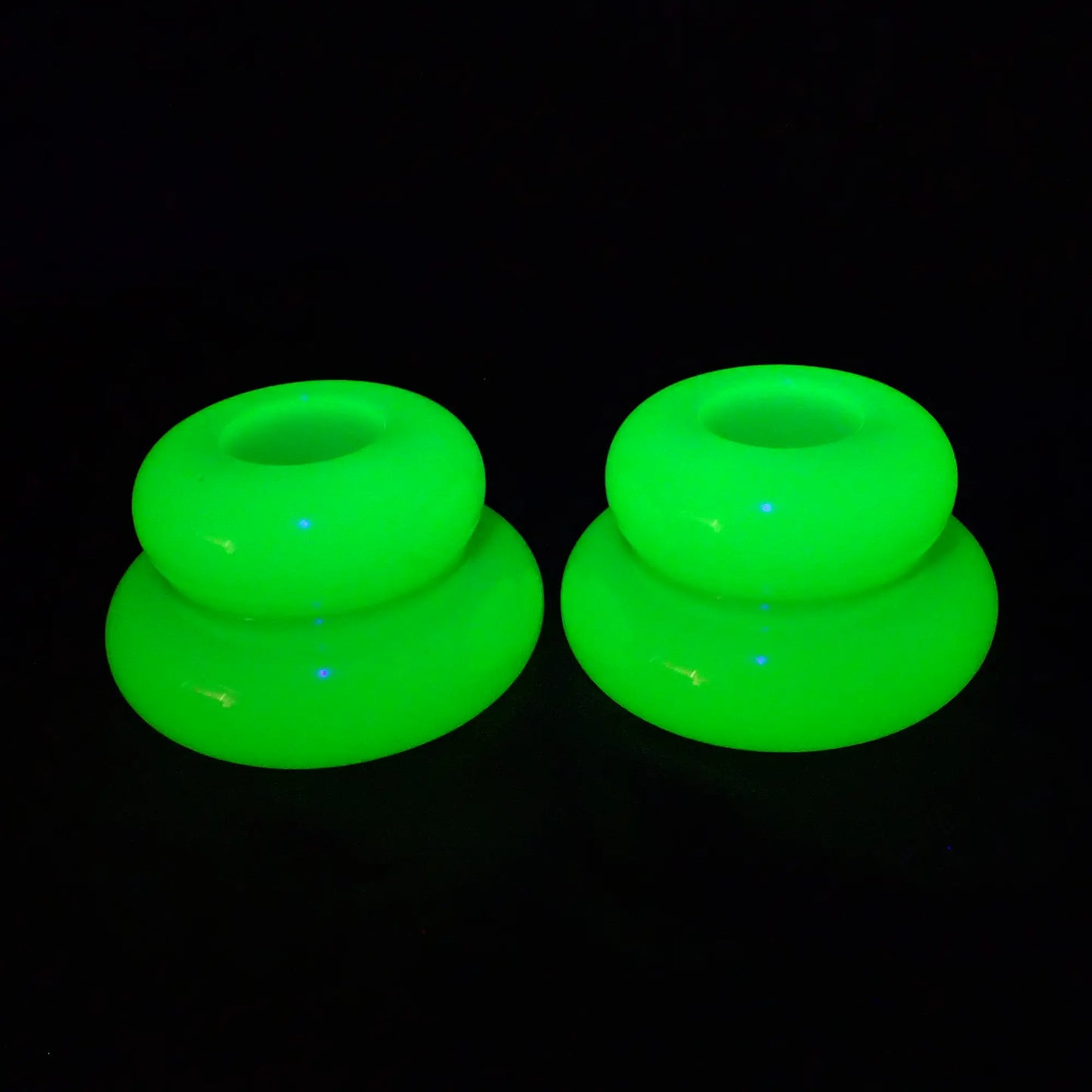 Photo showing the bright neon yellow puffy round double ring candlestick holders fluorescing bright green under a UV light.