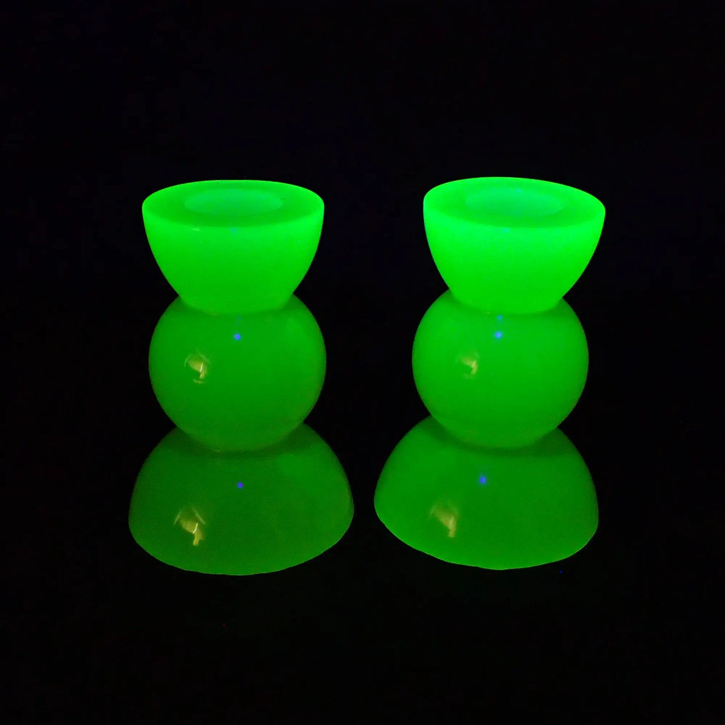 Photo showing the handmade resin neon yellow geometric candlestick holders fluorescing a bright neon green under a UV light.