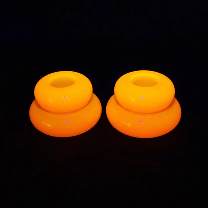 Photo of the handmade resin neon orange puffy round double ring candlestick holders fluorescing bright orange under a UV light.