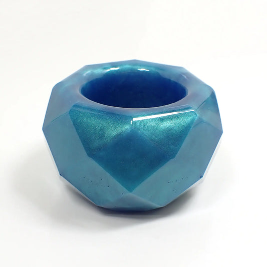 Side view of the small handmade succulent pot. The resin is aqua blue in color with flashes of light green. The decorative bowl has a faceted round shape with an octagon shape on top with a round opening.